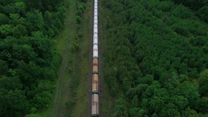 火车在原始生态绿色森林中运送原油罐。鸟瞰图。