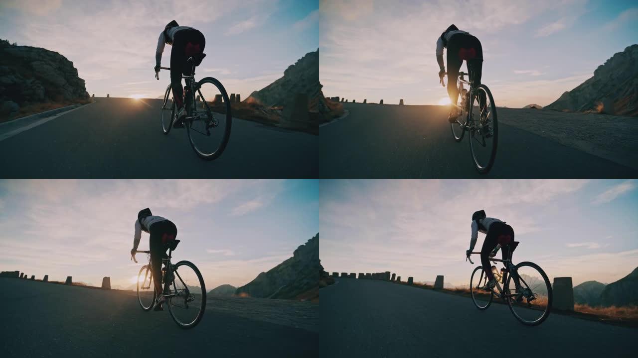 骑自行车的人在日出山上的道路上骑自行车