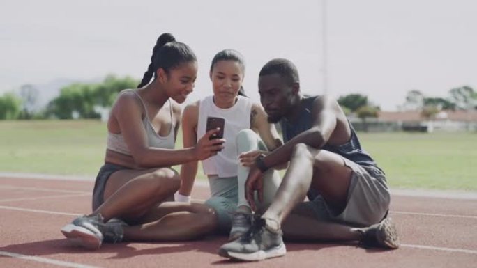 4k视频片段，展示了一群不同的田径运动员坐在一起并使用手机进行自拍照