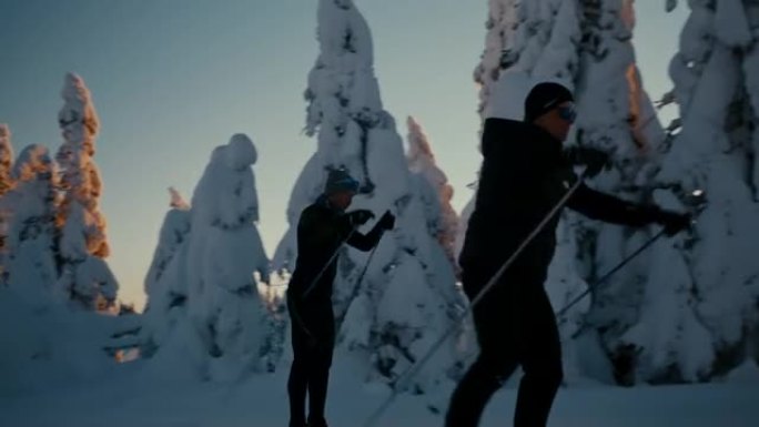 SLO MO两名男子越野滑雪运动员在日落时滑雪