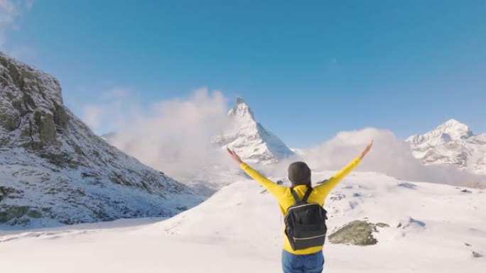 旅行者的空中无人机视图年轻女性在瑞士马特宏峰山顶上张开双臂向空中举起手臂。体验旅行与多样性。与阿尔法
