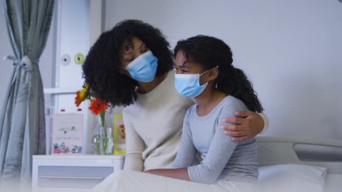 非裔美国母亲戴着口罩在医院里安慰女儿