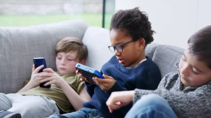 一群年轻的男孩和朋友一起在家里的手持设备上玩游戏