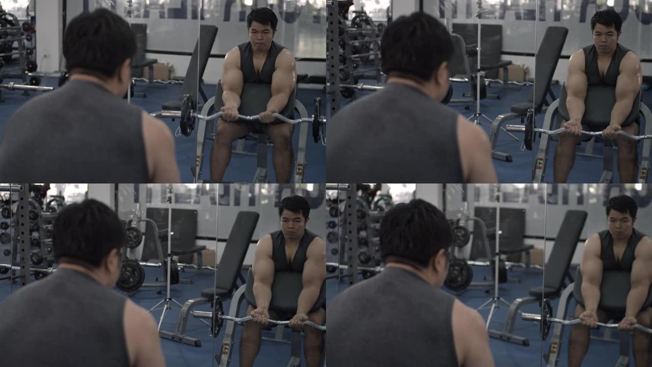 男子在健身房与杠铃一起锻炼，镜子的倒影