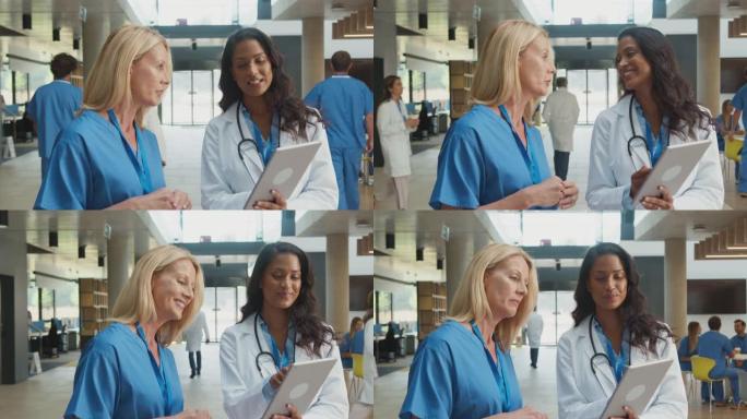 穿着白大褂和磨砂膏的女医务人员在医院非正式会议上使用数字平板电脑