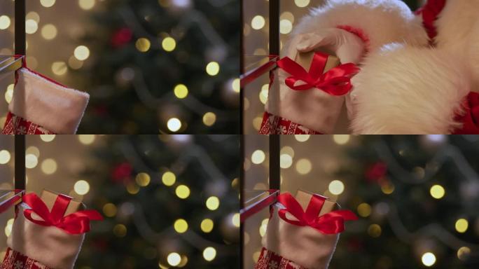 圣诞老人的手的特写镜头，将一个金色的礼品盒放在圣诞袜子中，背景是圣诞树