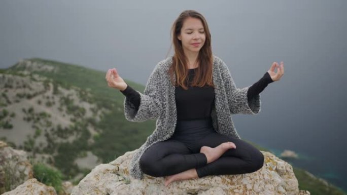 坐在悬崖上的瑜伽姿势冥想的年轻女子