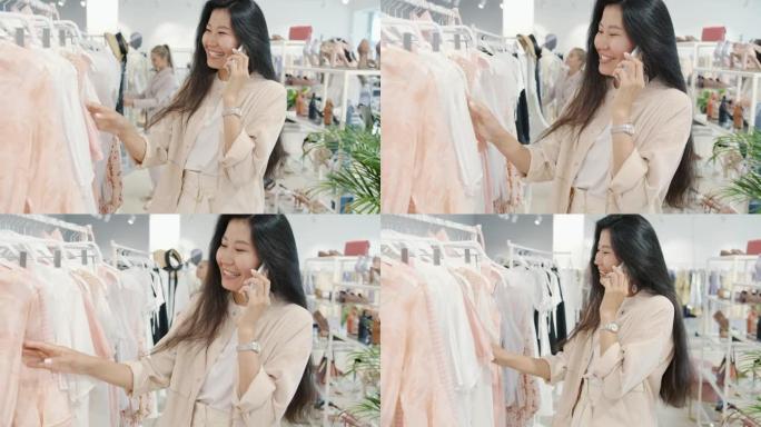 迷人的亚洲女人在手机上聊天，在时装店看衣服