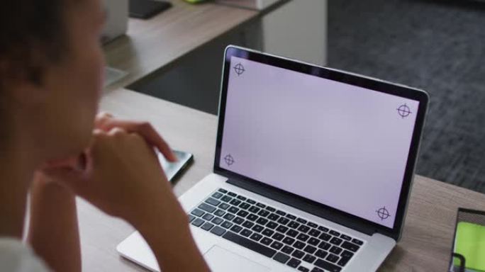 混血女商人坐在办公桌前，使用笔记本电脑，办公室屏幕上有复印空间
