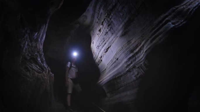 用灯探索洞穴的人背影男子探测