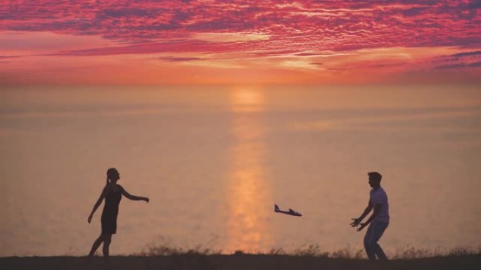男孩和女孩把玩具飞机扔在海景背景上