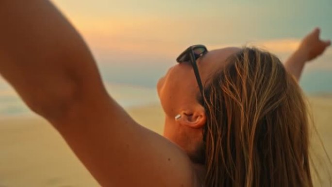 年轻女子女士在日落时欣赏海滩美景时将头发向后翻转