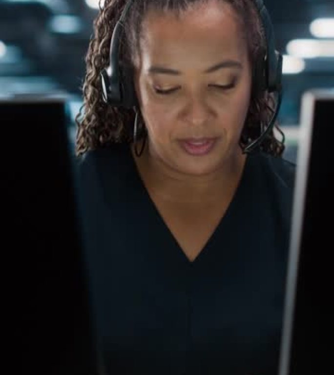 垂直屏幕。呼叫中心办公室: 友好的非裔美国女性技术客户支持专家的肖像在耳机上交谈，使用计算机。客户体