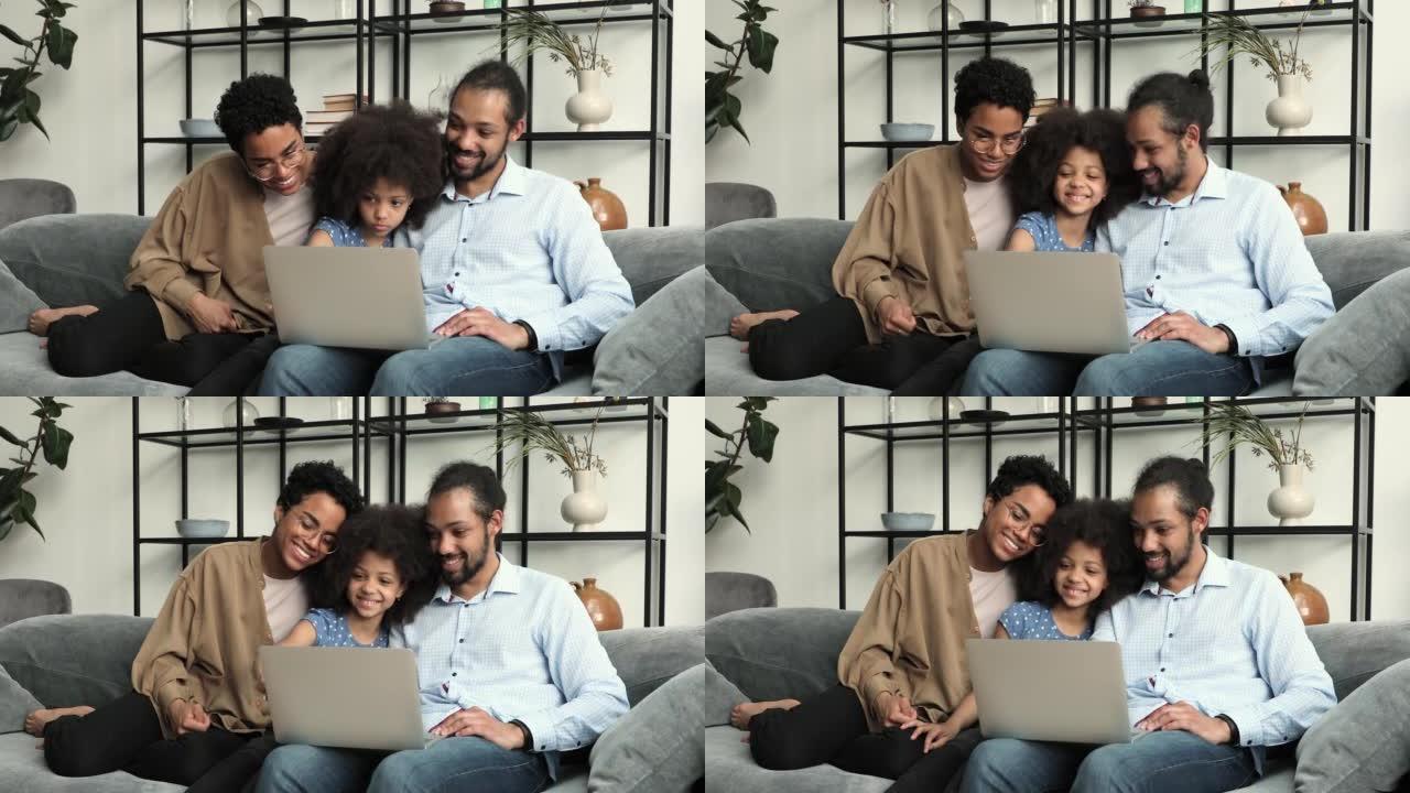 在沙发上拥抱非洲家庭在笔记本电脑上浏览网页