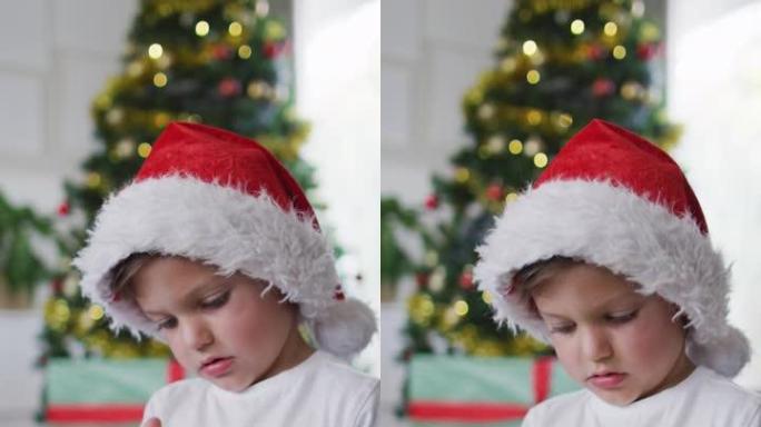一个戴着圣诞老人帽子的高加索男孩拿着雪球的垂直镜头