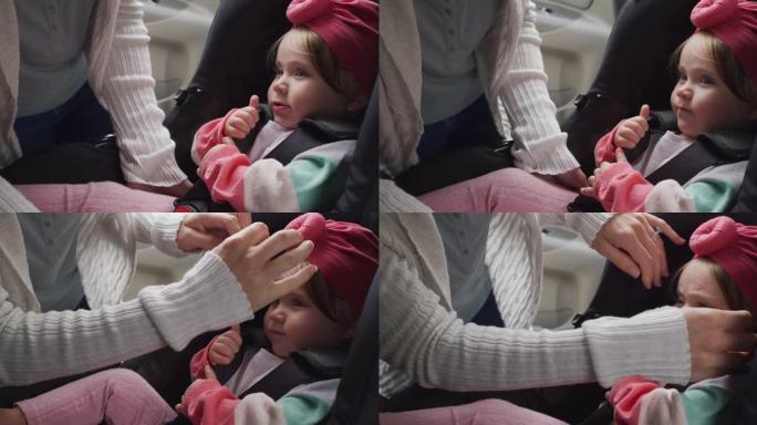 高加索母亲的中间部分将婴儿放在汽车的安全座椅上