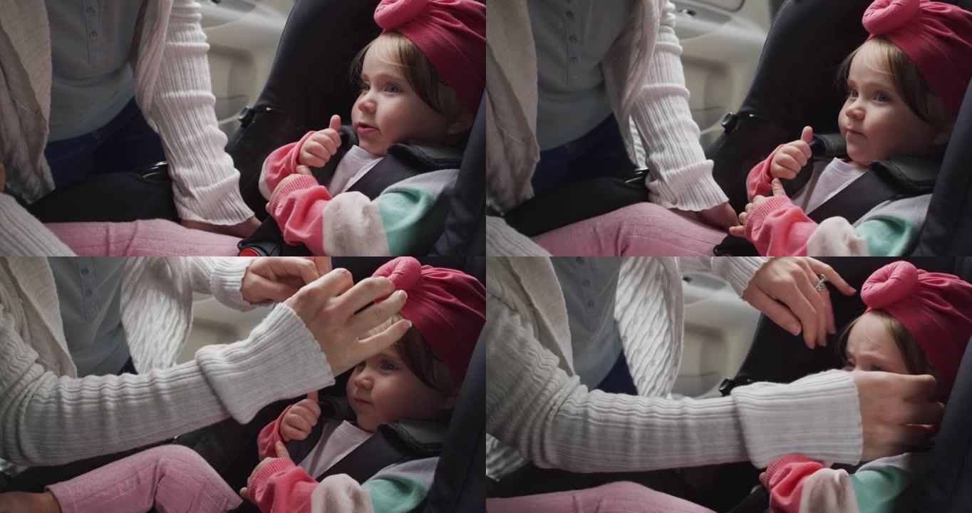 高加索母亲的中间部分将婴儿放在汽车的安全座椅上