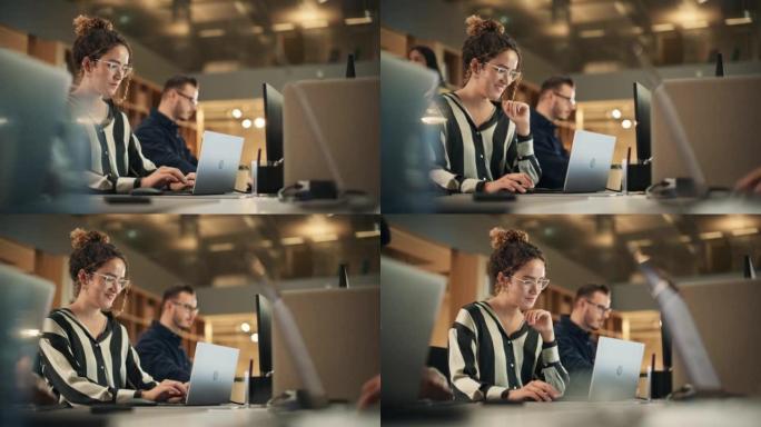 在现代明亮的办公室里，热情的西班牙裔年轻女子在电脑上工作的肖像。自信的人力资源代理在与同事在线合作时