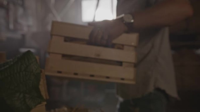 SLO MO Farmer在谷仓内携带一个装满玉米芯的板条箱