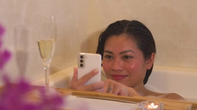 特写: 泡泡浴中的年轻女性为满杯香槟拍照