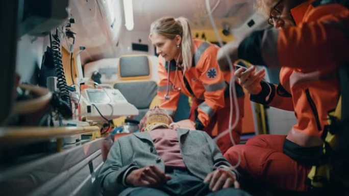 女性和男性EMS护理人员提供医疗帮助受伤的病人在去医疗保健医院的路上。急救助理在救护车上戴上无创通气