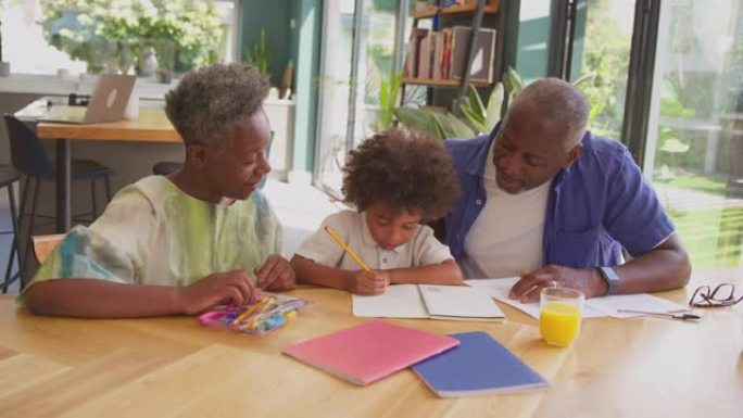 多代家庭，祖父母帮助孙子在家做作业，坐在桌边慢动作拍摄