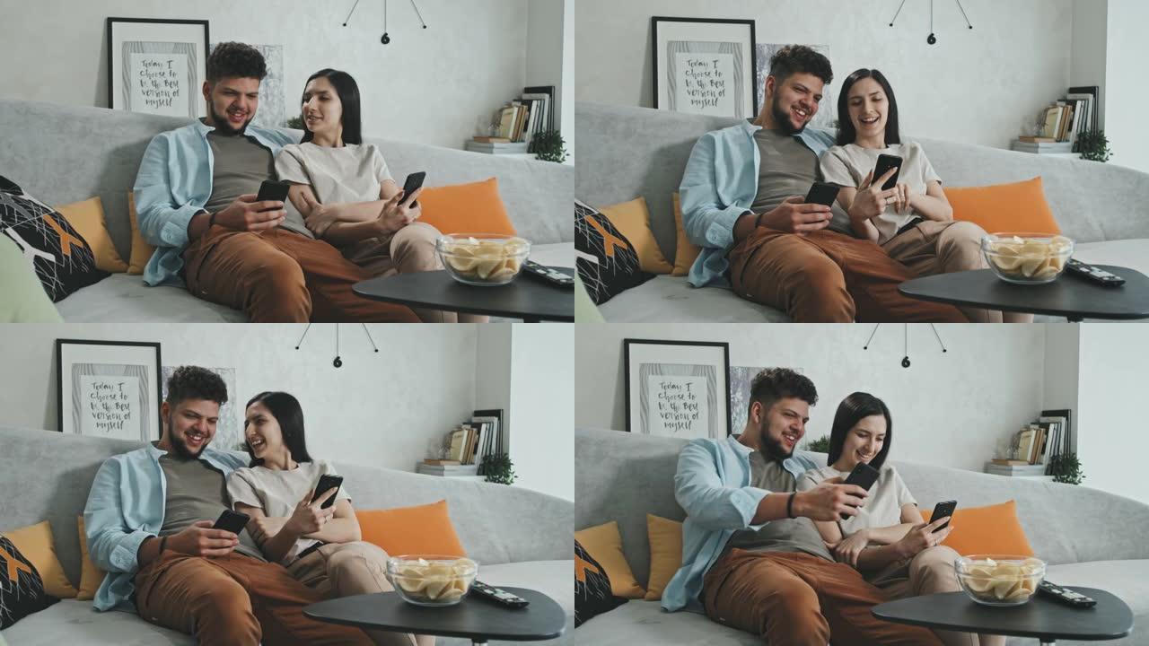 年轻夫妇在智能手机上观看媒体内容并大笑