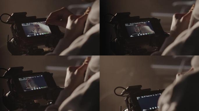 一位专业的视频操作员在拍摄电影时在相机的屏幕上观看素材