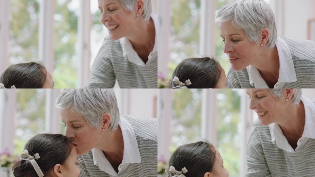 快乐的祖母轻轻地亲吻额头上的小女孩，表示对孙女的爱骄傲的奶奶在家里分享对孙子的爱