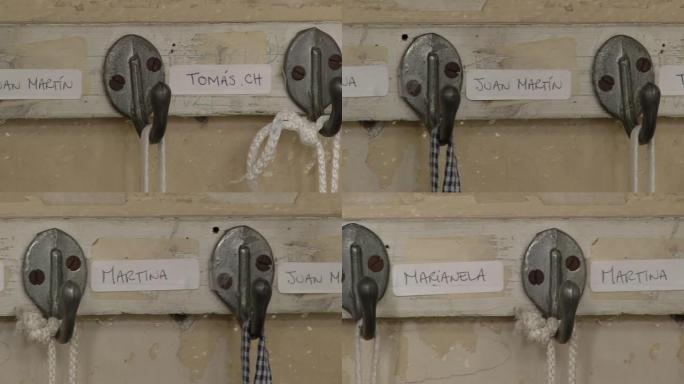 阿根廷布宜诺斯艾利斯幼儿园教室内的木条上安装有学生姓名的金属衣钩。特写。