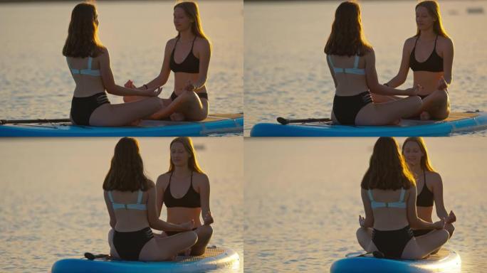 两名年轻女子在皮划艇上的莲花姿势冥想瑜伽