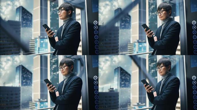 成功的时尚日本商人骑玻璃电梯到现代商务中心的办公室。英俊的男人在使用智能手机时微笑，写短信，在电梯中