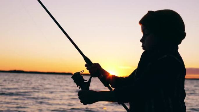 小孩在日落时钓鱼时正在处理钓鱼竿