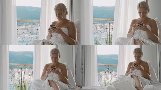 SLO MO Mid成年女性在酒店的床上使用智能手机