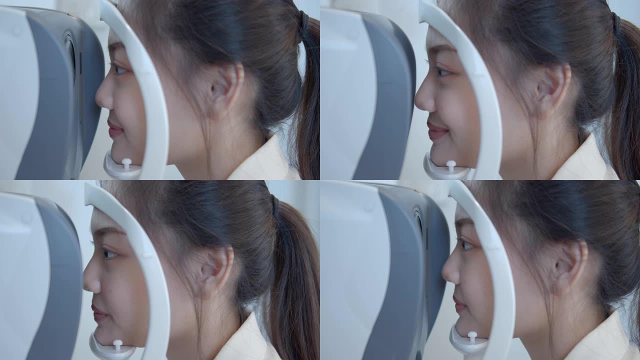 年轻的亚洲妇女在光学商店的医疗机器上进行眼睛测试，特写镜头