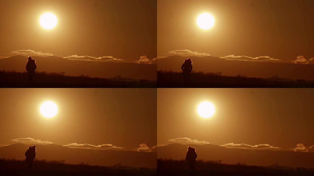 日落时在山上放松的剪影中的SLO MO WS女人