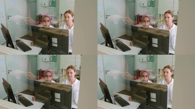 女放射科医生，助手看着MRI扫描控制室内的计算机屏幕