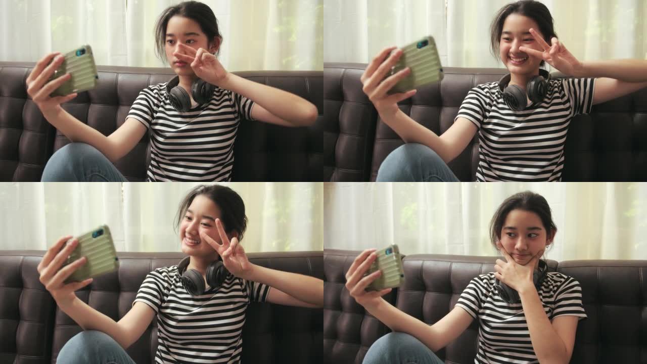 年轻的亚洲女孩试图在她的智能手机上摆姿势。自画像