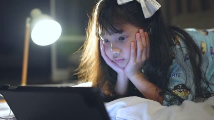 小女孩在家睡觉前在数字平板电脑上看卡通