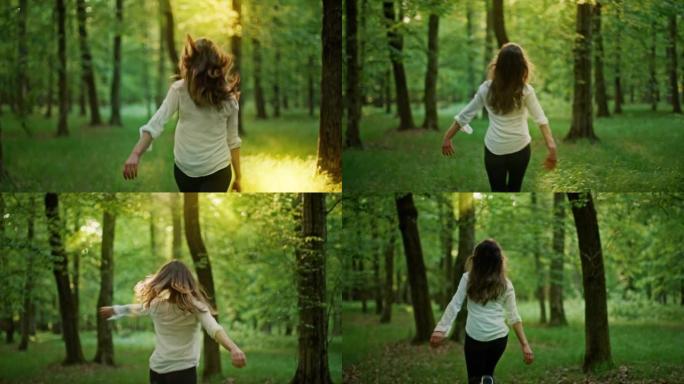 SLO MO欣喜若狂的女人在阳光明媚的森林中的绿色林间空地中旋转和弹跳