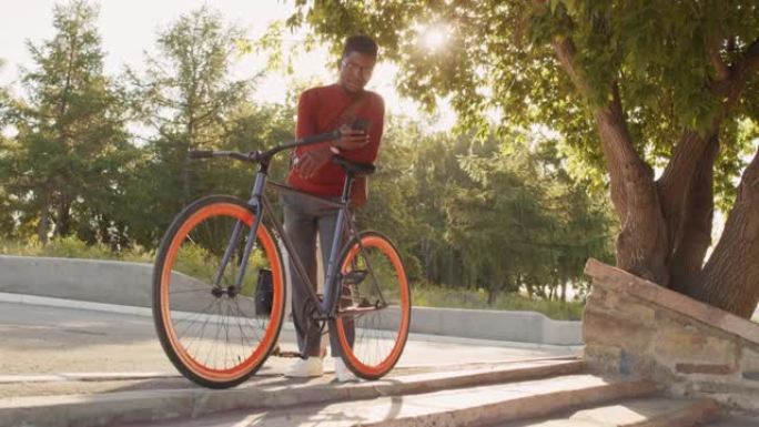 在户外使用智能手机骑自行车的非裔美国人
