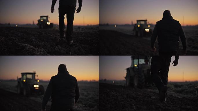 农民在日出时走在黑暗的农田里