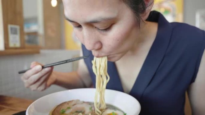 亚洲妇女在日本餐厅用筷子吃日本拉面