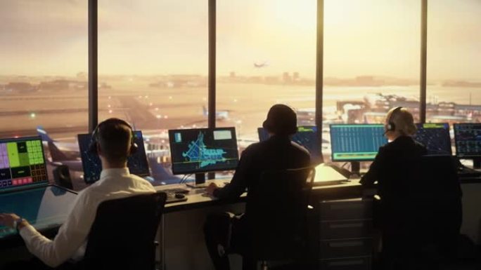 日落时在现代机场塔楼工作的多元化空中交通管制团队。办公室里满是台式电脑显示屏，配有导航屏幕、飞机起飞