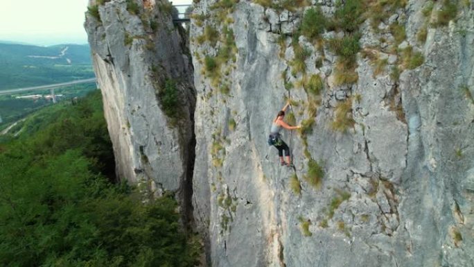复制空间: 一名女性攀岩者登上具有挑战性的悬崖的无人机视图