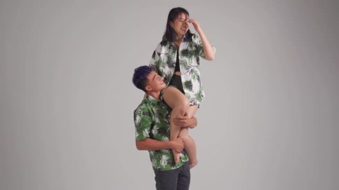 顽皮的亚洲中国男朋友肩扛女友夏季穿工作室拍摄与灰色背景