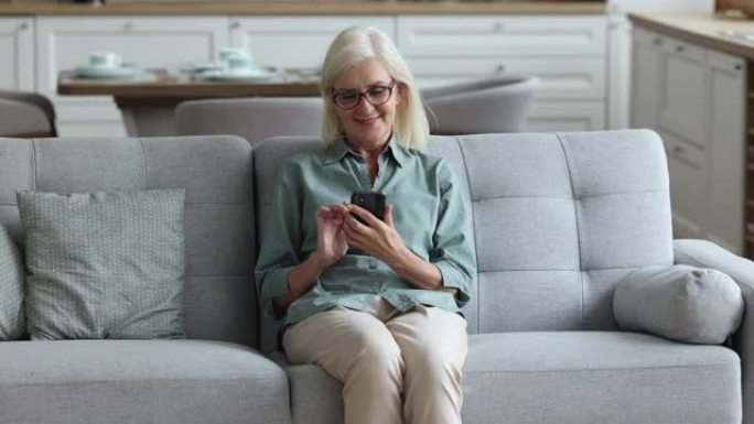 快乐的成熟女人使用现代智能手机在互联网上度过休闲