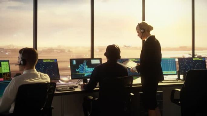 日落时在现代机场塔楼工作的多元化空中交通管制团队。办公室里满是台式电脑显示屏，配有导航屏幕、飞机起飞