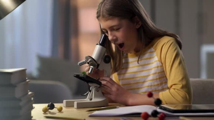 一个年轻女孩独自坐在家里并在做作业时使用显微镜的4k视频片段