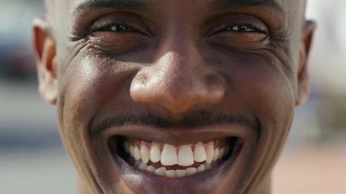 特写肖像快乐、兴奋和友好的黑人脸上带着牙齿微笑。英俊的非洲裔美国男性在开玩笑或有趣的事情上笑着或用皱